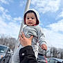toddler, child, hoodie, grey_clothing, hand, outdoor, sky, clouds, car, parking_lot, person, casual_wear, portrait, cute, baby, holding, face, expression, young_child, daylight