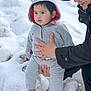Endrick is registered to the contest to win money with this photo: toddler, child, adult, snow, winter_clothing, hoodie, pants, blue_socks, outdoor, cold_weather, support, smile, cap, jackets, hand, standing, person, nature, daylight, portrait