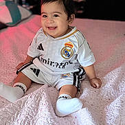 Endrick joined the competition — help win amazing prizes! baby, bed, blanket, child, clothing, cute, face, happy, head, indoor, infant, person, portrait, real_madrid, sitting, smile, soccer_outfit, sportswear, white_socks, young_child