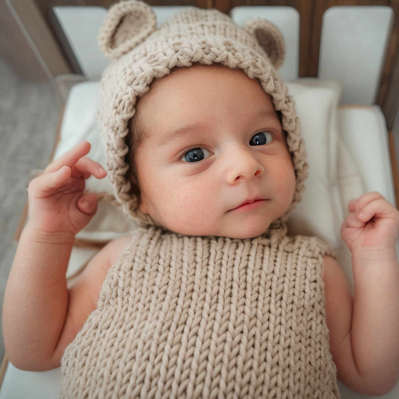 Shâyân joined the competition — help win amazing prizes! baby, infant, knitted_hat, bear_ears, knitted_sweater, cute, child, portrait, indoor, cushion, wooden_bed, neutral_colors, curious_expression, small_hands, closeup, soft_lighting, cozy, newborn, face, lying_down