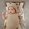 Shâyân is registered to the contest to win money with this photo: baby, infant, knitted_clothing, bear_ears, teddy_bear, mini_bed, wooden_bed, cute, cozy, soft_lighting, portrait, child, smiling, hand, lying_down, indoors, warm_colors, fabric, toy, sleepwear