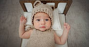 Shâyân joined the competition — help win amazing prizes! baby, infant, knitted_hat, knitted_outfit, bear_ears, wooden_bed, pillow, lying_down, cute, wide_eyes, raised_arms, indoors, portrait, child, adorable, soft_lighting, neutral_colors, cozy, sleepwear, baby_fashion