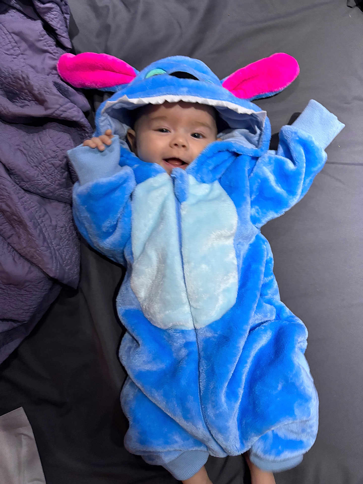Billie Jean is registered to the contest to win money with this photo: baby, bed, blanket, blue, child, costume, cute, fabric, face, happy, hood, indoors, infant, lying_down, person, pink, plush, sleeve, small, smiling