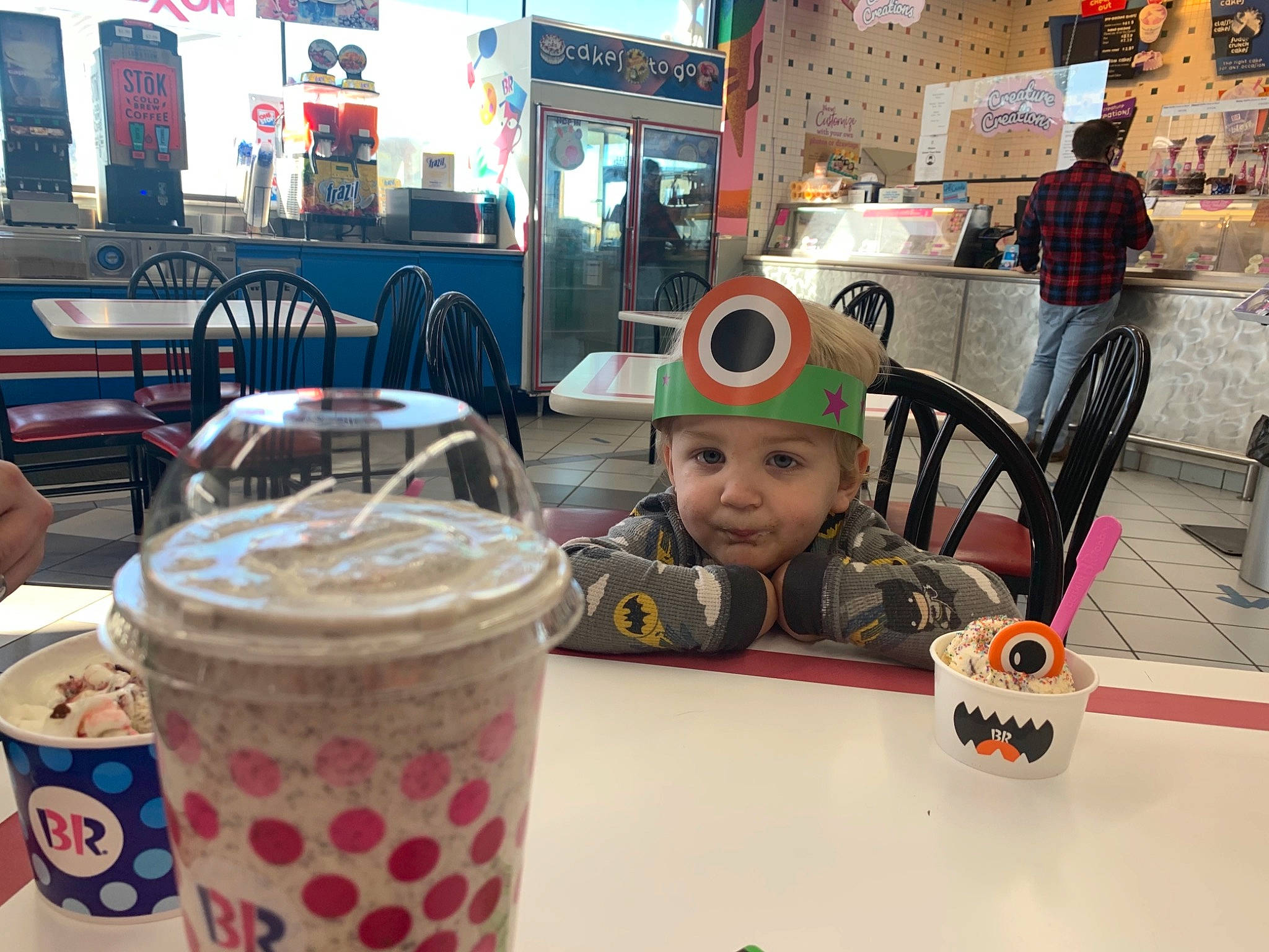 Dexter is registered to the contest to win money with this photo: baby, chair, coffee, cup, drink, drinking_straw, drinkware, event, food, frappe_coffee, fun, headwear, iced_coffee, ingredient, milkshake, non_alcoholic_beverage, person, sweetness, table, toddler