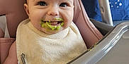 Sofia joined the competition — help win amazing prizes! baby, high_chair, bib, food, messy, smile, child, indoor, feeding, face, person, happy, green_food, cute, infant, seat, pink, plastic, table, tongue