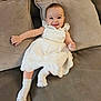 Sofia joined the competition — help win amazing prizes! baby, child, smiling, white_dress, socks, couch, pillows, indoor, happy, infant, cute, relaxing, furniture, person, portrait, cozy, soft, comfort, sitting, home
