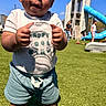 toddler, child, playground, outdoor, grass, slide, climbing_structure, sunny, blue_sky, shorts, tshirt, plastic_lid, holding, people, playing, recreation, daytime, kids, fun, leisure