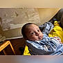 Kamaz is registered to the contest to win money with this photo: baby, infant, blue_outfit, yellow_blanket, curious, wide_eyes, indoor, couch, wooden_floor, cozy, person, child, newborn, portrait, casual, home, soft_lighting, clothing, relaxed, seated