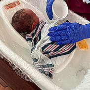 Saria joined the competition — help win amazing prizes! newborn, baby, hospital, bath, gloves, nurse, tub, blanket, water, infant, care, medical, person, healthcare, wrapped, wooden_floor, plastic, gentle, cleaning, swaddled