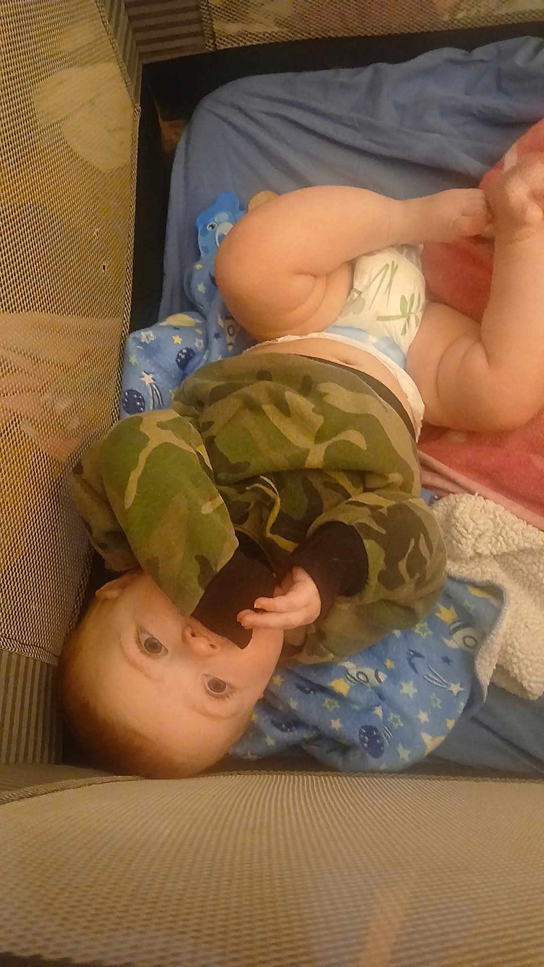 Arthur joined the competition — help win amazing prizes! baby, infant, child, camo_clothing, hoodie, playpen, blanket, toy, diaper, blue_blanket, pink_blanket, soft_toy, face, fingers, lying_down, indoor, cute, curious, sleeping_area, baby_care