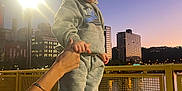 Carmello is registered to the contest to win money with this photo: toddler, child, person, grey_tracksuit, nike_logo, black_shoes, hand_holding, yellow_bridge, city_skyline, evening, streetlamp, river, reflection, urban, outdoor, railing, buildings, sunset, sky, casual_clothing
