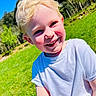 blonde_hair, blue_sky, boy, casual_clothing, child, daylight, grass, grass_field, greenery, happy, nature, outdoor, person, portrait, rosy_cheeks, smiling, sunny, trees, white_tshirt, young