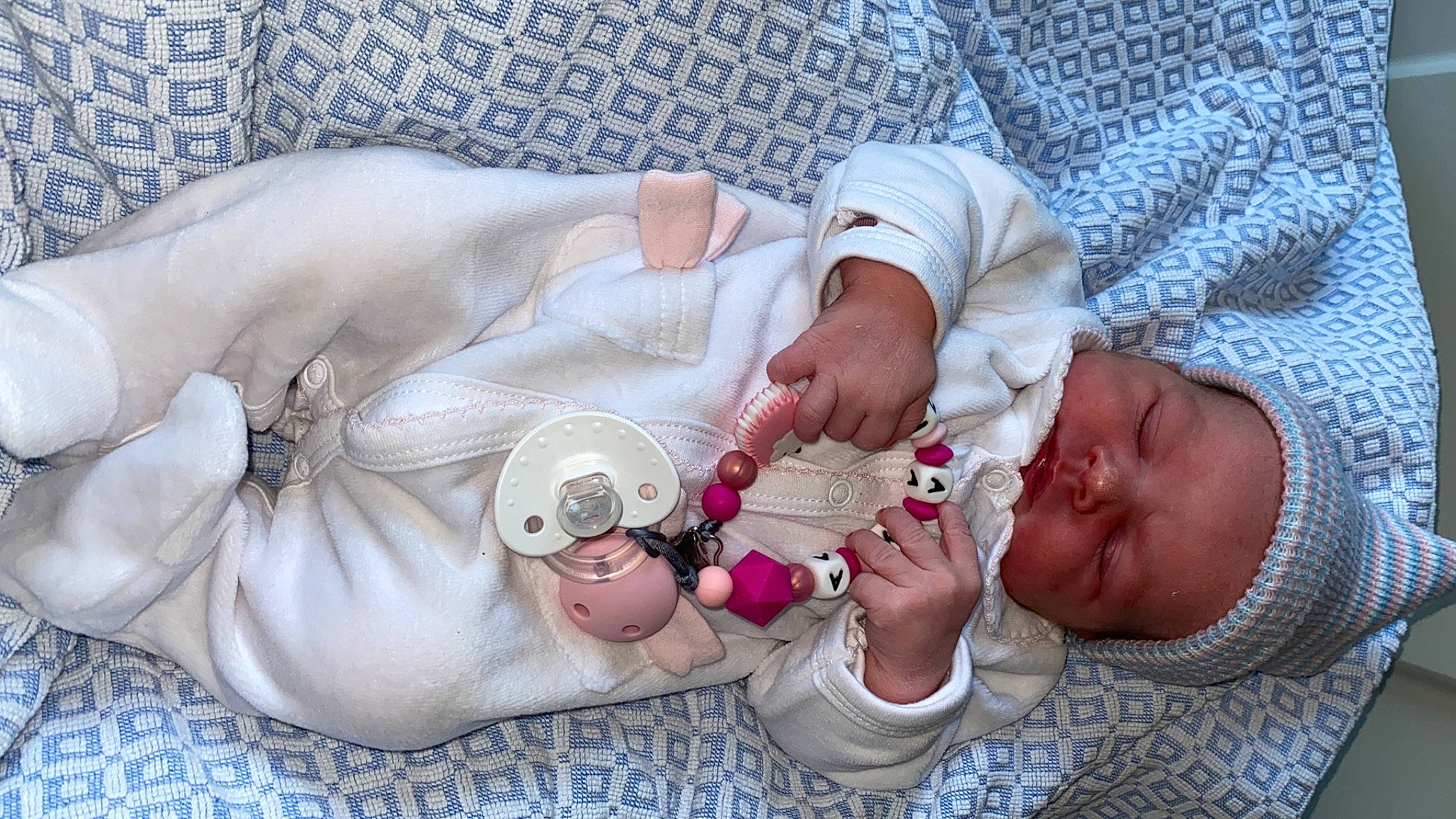 Inaya a rejoint le concours — aidez-le/la à gagner de superbes lots ! abdomen, arm, baby, baby_products, baby_sleeping, baby_toddler_clothing, chest, child, comfort, fashion_accessory, hand, human_body, jewellery, linens, nail, pattern, person, pink, skin, thumb