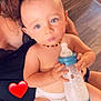baby, blue_eyes, casual, child, closeup, cute, diaper, flooring, hand, heart_emoji, holding, indoor, infant, milk_bottle, necklace, person, sitting, skin, wallpaper, young