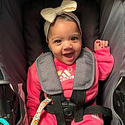 Amilya is registered to the contest to win money with this photo: baby, child, smiling, pink_clothing, headband, bow, stroller, seatbelt, adidas, happy, infant, cute, portrait, sitting, eyes, face, clothing, baby_girl, indoor, baby_accessory