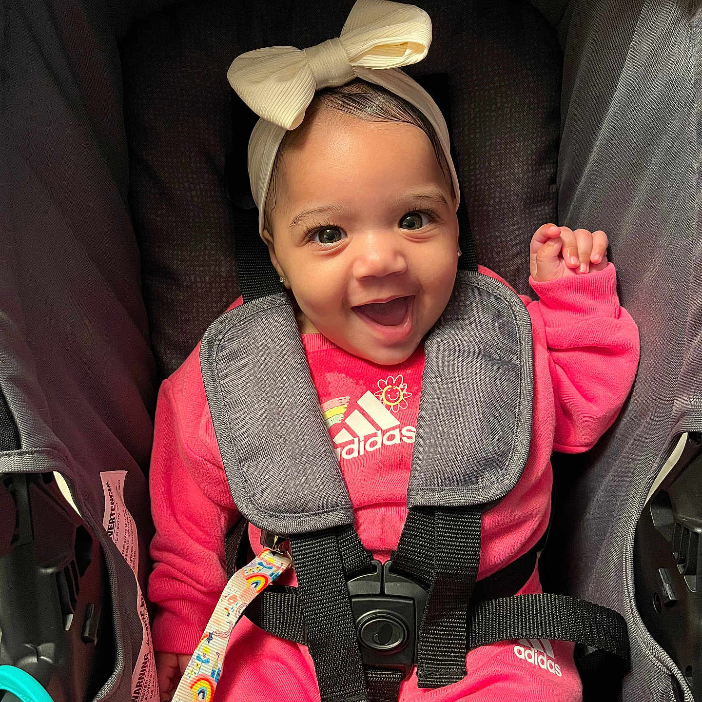 Amilya is registered to the contest to win money with this photo: adidas, baby, baby_accessory, baby_girl, bow, child, clothing, cute, eyes, face, happy, headband, indoor, infant, pink_clothing, portrait, seatbelt, sitting, smiling, stroller