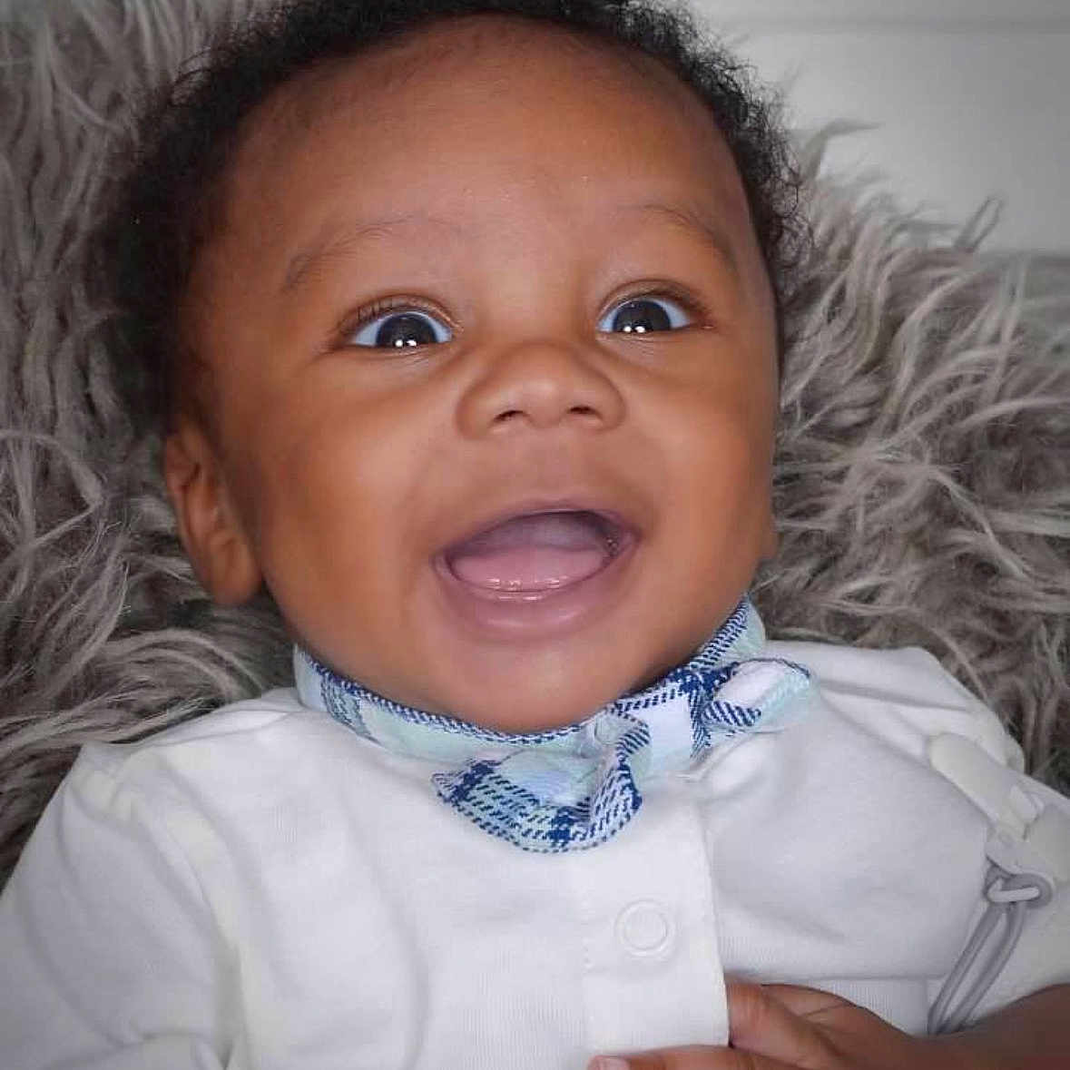 Josiah is registered to the contest to win money with this photo: baby, smiling, infant, face, portrait, happy, clothing, bow_tie, white_shirt, hand, fuzzy_blanket, close_up, cute, child, young, expression, indoor, person, skin, eyes