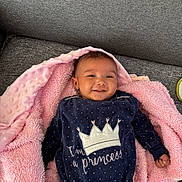 Luna participe au concours pour gagner de l'argent avec cette photo : baby, infant, blanket, pink_blanket, sofa, couch, smile, crown, onesie, clothing, portrait, lying_down, cheeks, head, hair, eyes, hand, fabric, polka_dot, indoor