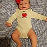 Aurora joined the competition — help win amazing prizes! baby, infant, child, smiling, portrait, lying_down, red_bow, hair_bow, onesie, apple_design, blanket, patterned_blanket, bed, indoor, happy, face, arms, legs, warm_lighting, family_photo