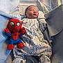 newborn, baby, sleeping, onesie, animal_print, blanket, plush_toy, spiderman, soft_light, cozy, infant, bed, cute, resting, indoor, child, toy, peaceful, snug, portrait