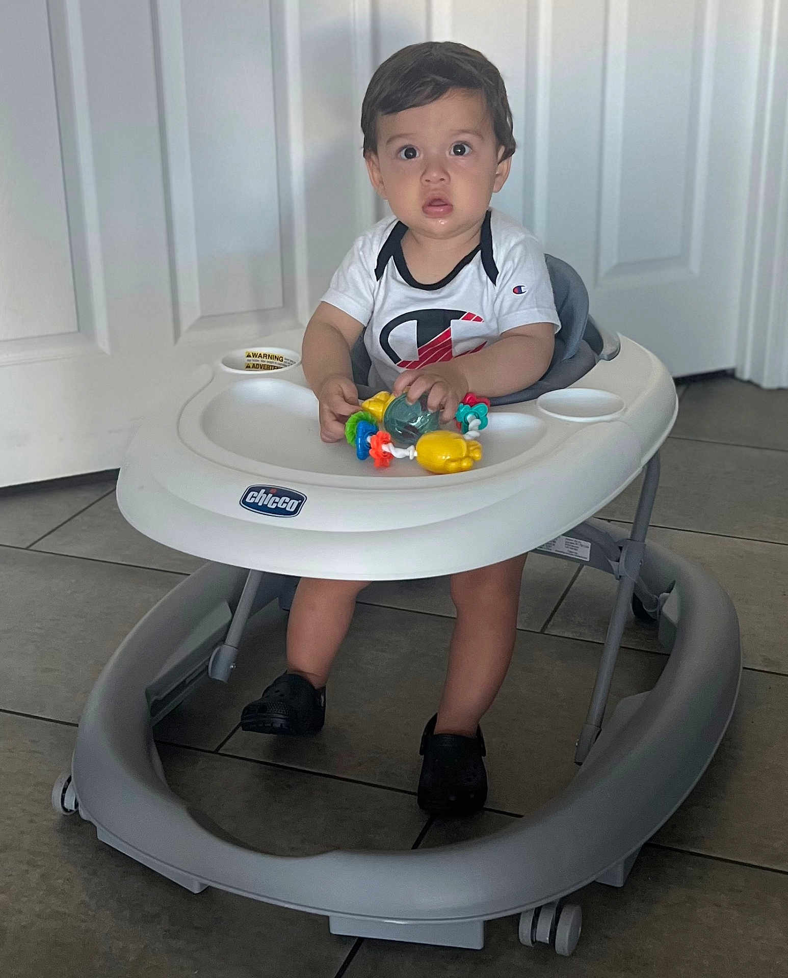 Julius Arceo joined the competition — help win amazing prizes! toddler, baby_walker, toy, indoor, child, floor_tile, white_door, curious, sitting, clothing, shoes, plastic, childrens_toy, person, footwear, expression, play, home, walker, young_child