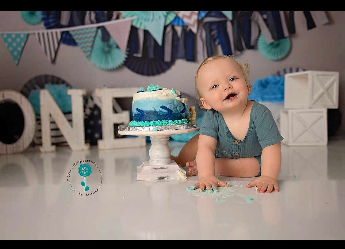 Samuel is registered to the contest to win money with this photo: baby, birthday, cake, blue, white, celebration, child, decorations, festive, floor, happy, messy, one, photography, portrait, smiling, studio, toddler, young, cute