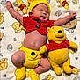 baby, sleeping, crocheted_clothing, yellow_hat, red_shirt, yellow_booties, plush_toy, winnie_the_pooh, blanket, patterned_blanket, child, infant, cute, soft_toy, lying_down, cozy, indoors, smiling_toy, button_clothing, adorable