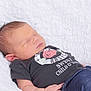 Terry is registered to the contest to win money with this photo: baby, newborn, sleeping, infant, tshirt, rose, text, jeans, clothing, white_blanket, soft_texture, peaceful, portrait, child, cute, resting, indoors, human, casual_wear, closeup