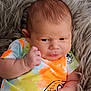 Terry joined the competition — help win amazing prizes! baby, infant, face, hand, fist, colorful_clothing, tie_dye, onesie, blanket, fur_texture, skin, expression, portrait, child, newborn, cute, indoors, resting, young, person