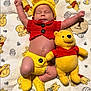 baby, infant, sleeping, crochet_clothing, yellow_hat, red_shirt, yellow_booties, plush_toy, winnie_the_pooh, blanket, baby_outfit, newborn, wooden_sign, cute, resting, child, soft_toy, patterned_blanket, lying_down, adorable