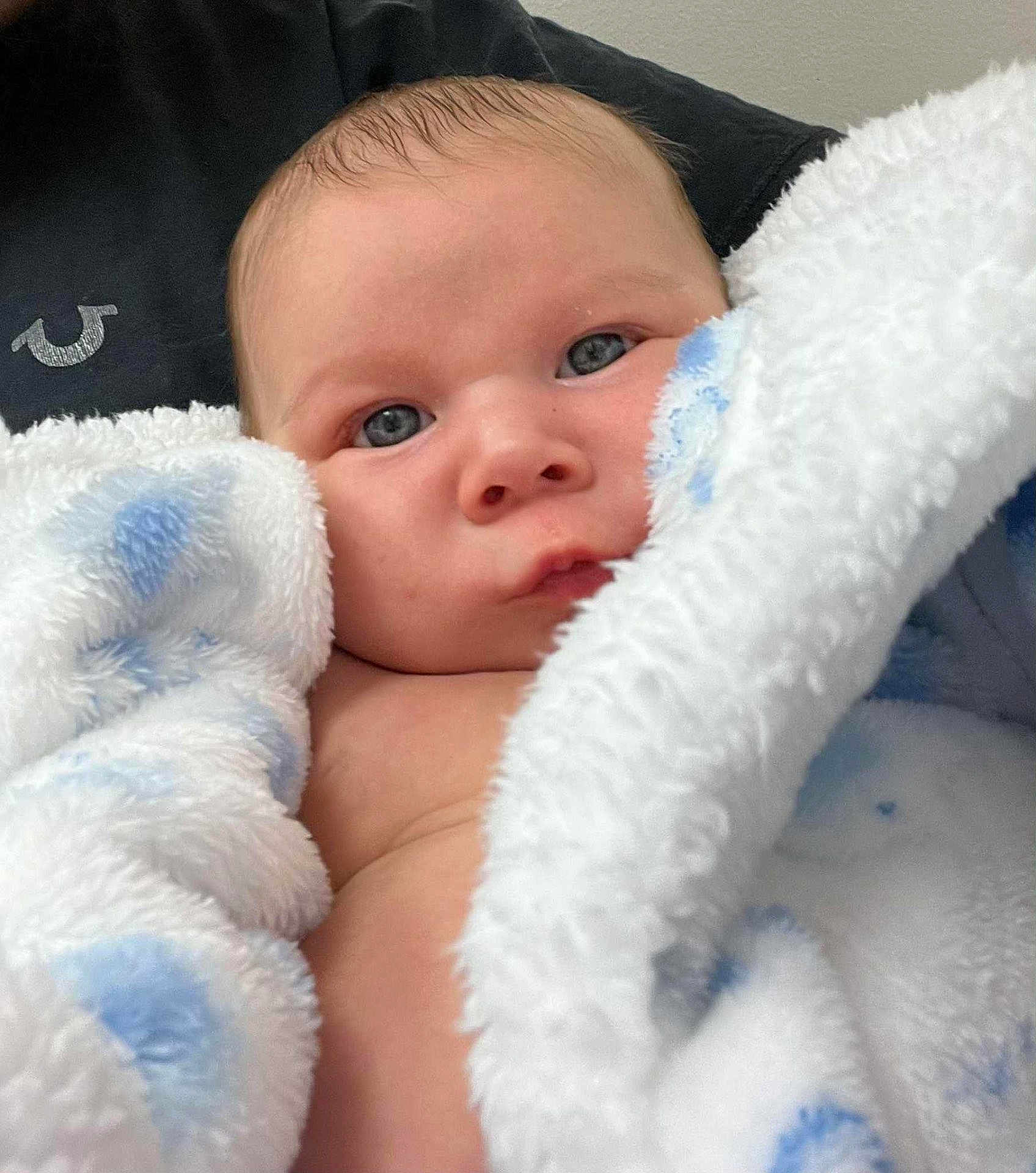 Terry joined the competition — help win amazing prizes! baby, infant, face, blanket, blue, white, soft_texture, close_up, newborn, skin, eyes, cute, child, wrapped, cozy, portrait, indoors, human, expression, young