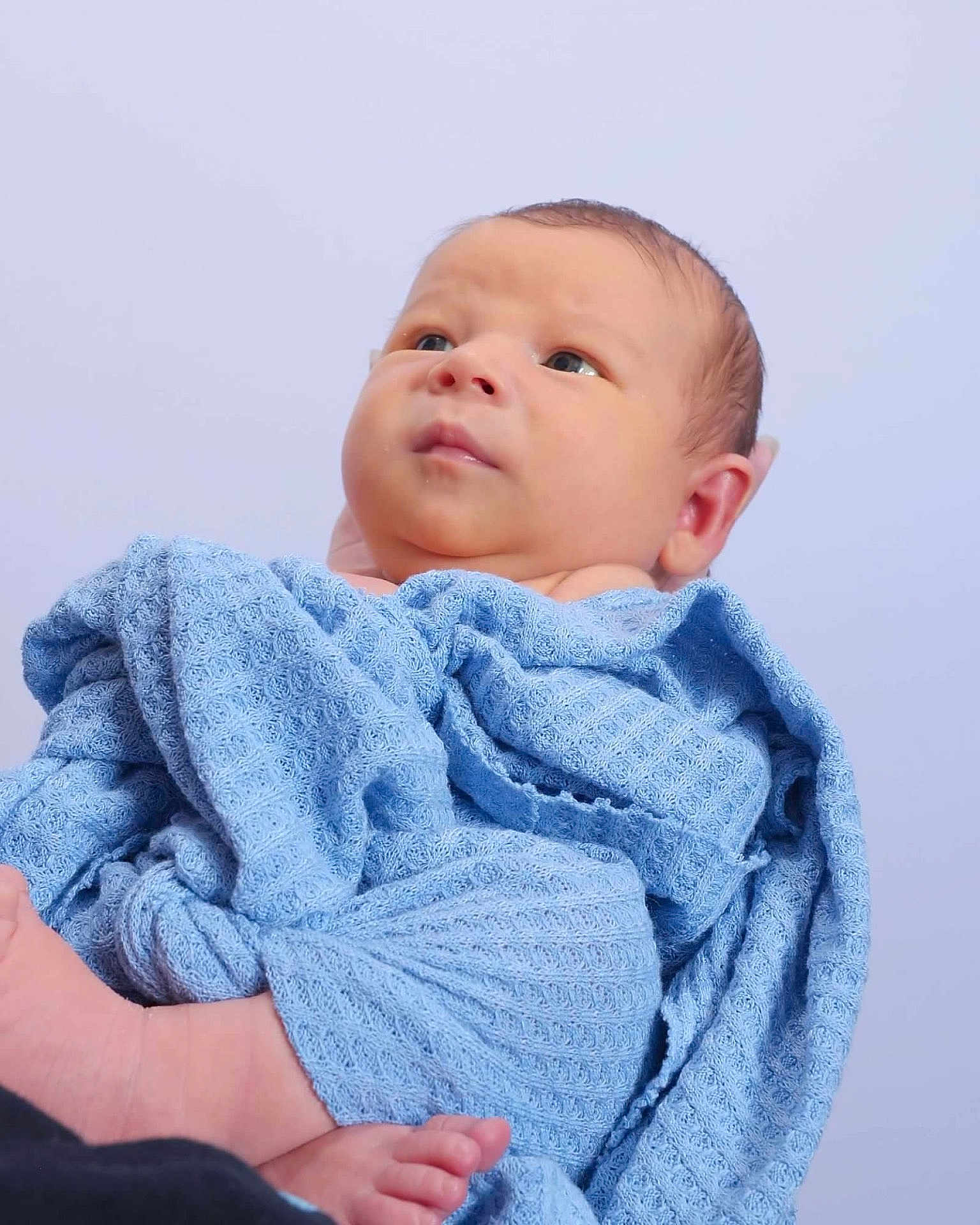 Terry is registered to the contest to win money with this photo: baby, infant, blue_blanket, wrapped, portrait, newborn, soft_texture, curious_eyes, peaceful, head, face, skin, foot, hand, closeup, indoor, person, child, cute, background