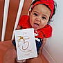 Aria participe au concours pour gagner de l'argent avec cette photo : baby, child, infant, red_headband, red_shirt, crib, milestone_card, tongue_out, smiling, sitting, indoors, white_bars, orange_bed, cute, happy, person, portrait, curly_hair, headband, skin