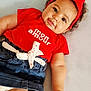 baby, infant, child, curly_hair, red_headband, red_shirt, denim_skirt, white_bow, cute, smiling, lying_down, soft_light, portrait, indoor, adorable, fashion, clothing, face, hand, skin