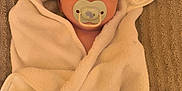 Maélan a rejoint le concours — aidez-le/la à gagner de superbes lots ! baby, pacifier, towel, hooded_towel, white, wrapped, infant, face, cute, lying_down, blanket, soft, child, sleepy, texture, brown, comfort, resting, indoors, portrait