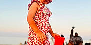 Alma a rejoint le concours — aidez-le/la à gagner de superbes lots ! child, toddler, beach, sand, red_cup, sunset, dress, strawberry_pattern, barefoot, sea, sky, outdoor, vacation, summer, play, toy, people, relaxation, holiday, portrait