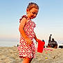 child, toddler, beach, sand, red_cup, sunset, dress, strawberry_pattern, barefoot, sea, sky, outdoor, vacation, summer, play, toy, people, relaxation, holiday, portrait
