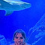 child, smile, girl, aquarium, shark, water, underwater, rocks, blue, animal, marine_life, portrait, jacket, face, young, happy, nature, sea_creature, leisure, indoor