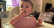 Amyalee joined the competition — help win amazing prizes! cake, child, colorful, couch, curly_hair, curtain, eating, face, food, hand, high_chair, indoor, living_room, person, pillow, pink_bib, plant, table, toddler, window