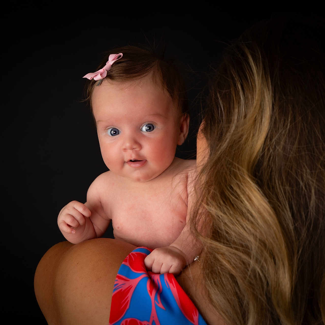 Esmé is registered to the contest to win money with this photo: adult, baby, back_view, blue_eyes, child, closeup, colorful_clothing, curious, expression, hair, head, holding, infant, person, pink_bow, portrait, shoulder, skin, studio, woman