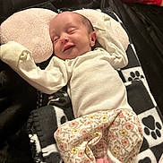 Remi is registered to the contest to win money with this photo: baby, blanket, child, comfort, cozy, cute, floral_pants, indoor, infant, newborn, peaceful, person, pillow, pink_socks, portrait, resting, sleeping, smiling, soft_lighting, white_top