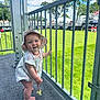 Maelle is registered to the contest to win money with this photo: baby, babylaughing, bus, clothing, face, fence, grass, happy, hat, head, nature, outdoors, park, person, photography, plant, portrait, sitting, transportation, vehicle
