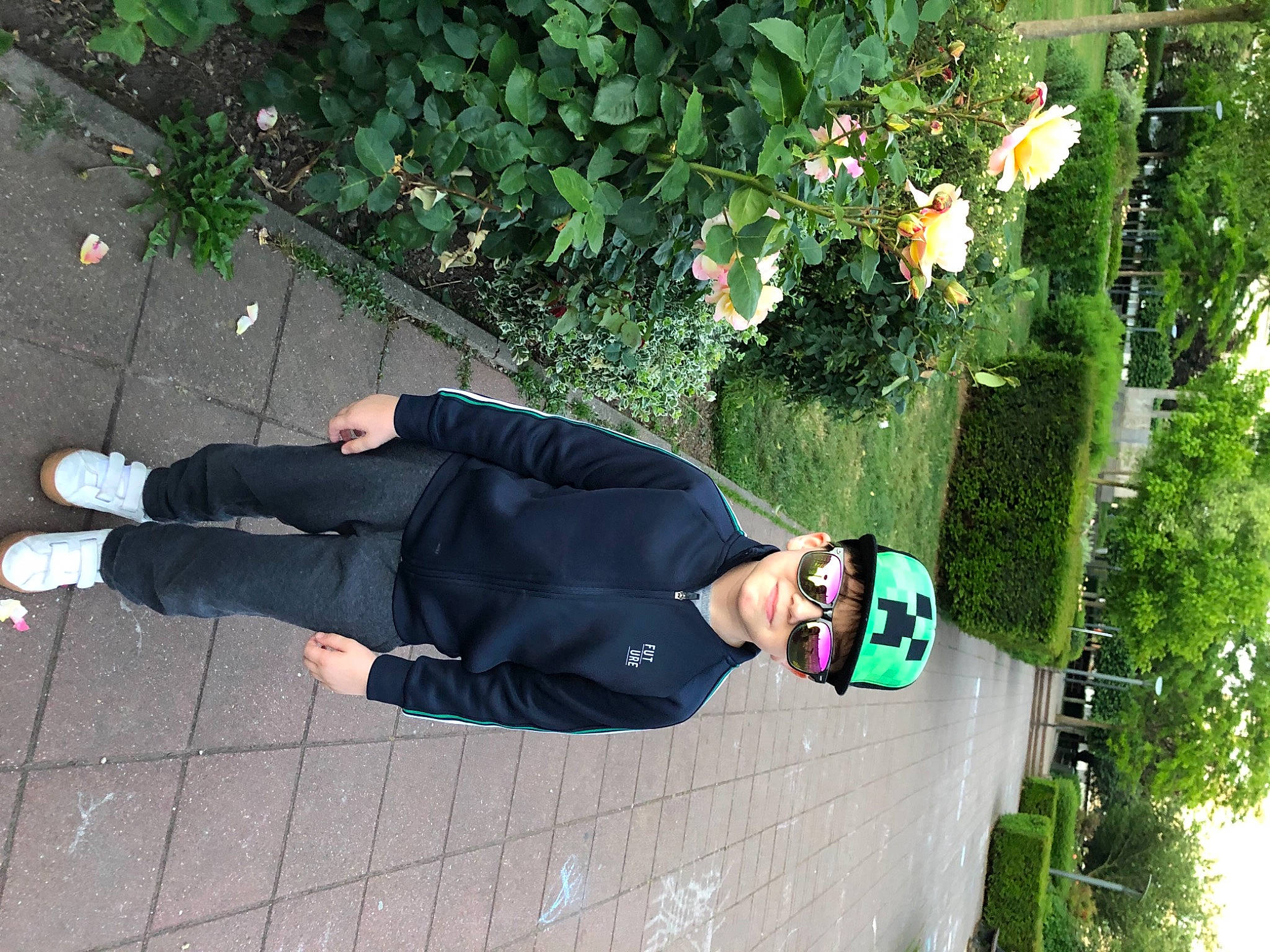 Georges participe au concours pour gagner de l'argent avec cette photo : flooring, flower, fun, grass, hat, headwear, knee, leisure, pedestrian, person, plant, shrub, sidewalk, smile, street_fashion, suit, tree, walking_shoe