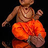 Avika is registered to the contest to win money with this photo: baby, child, orange_pants, beads, reflection, black_background, smiling, portrait, traditional_jewelry, anklets, bracelets, cute, sitting, lock_screen, phone_screen, time_display, date_display, indoor, happy, reflection_surface