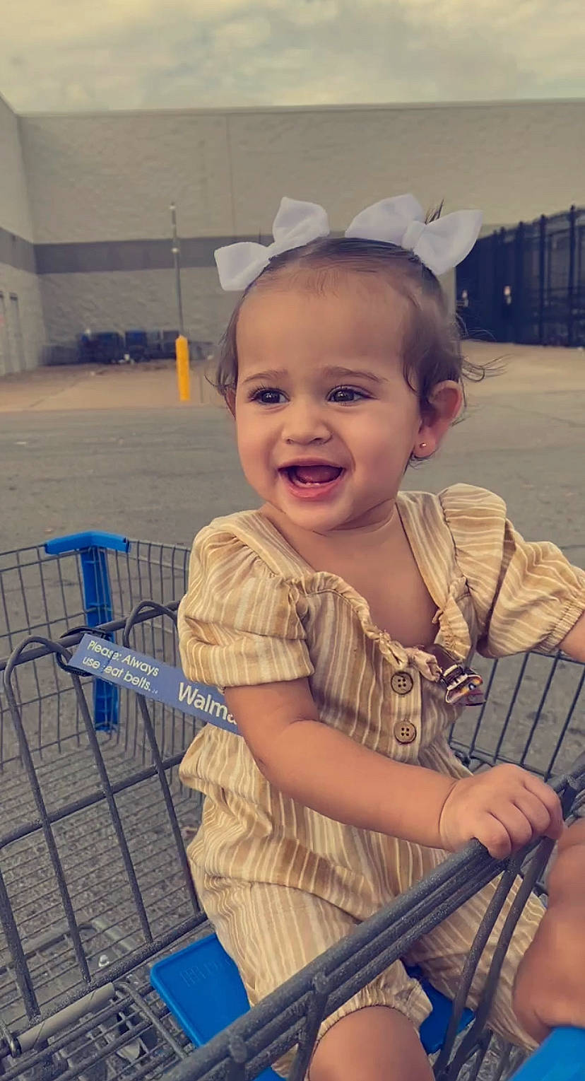 Madelyn is registered to the contest to win money with this photo: baby, baby_products, baby_toddler_clothing, cart, child, electric_blue, fashion_accessory, fun, happy, headband, headpiece, iris, joy, person, shopping_cart, sitting, skin, smile, standing, tire