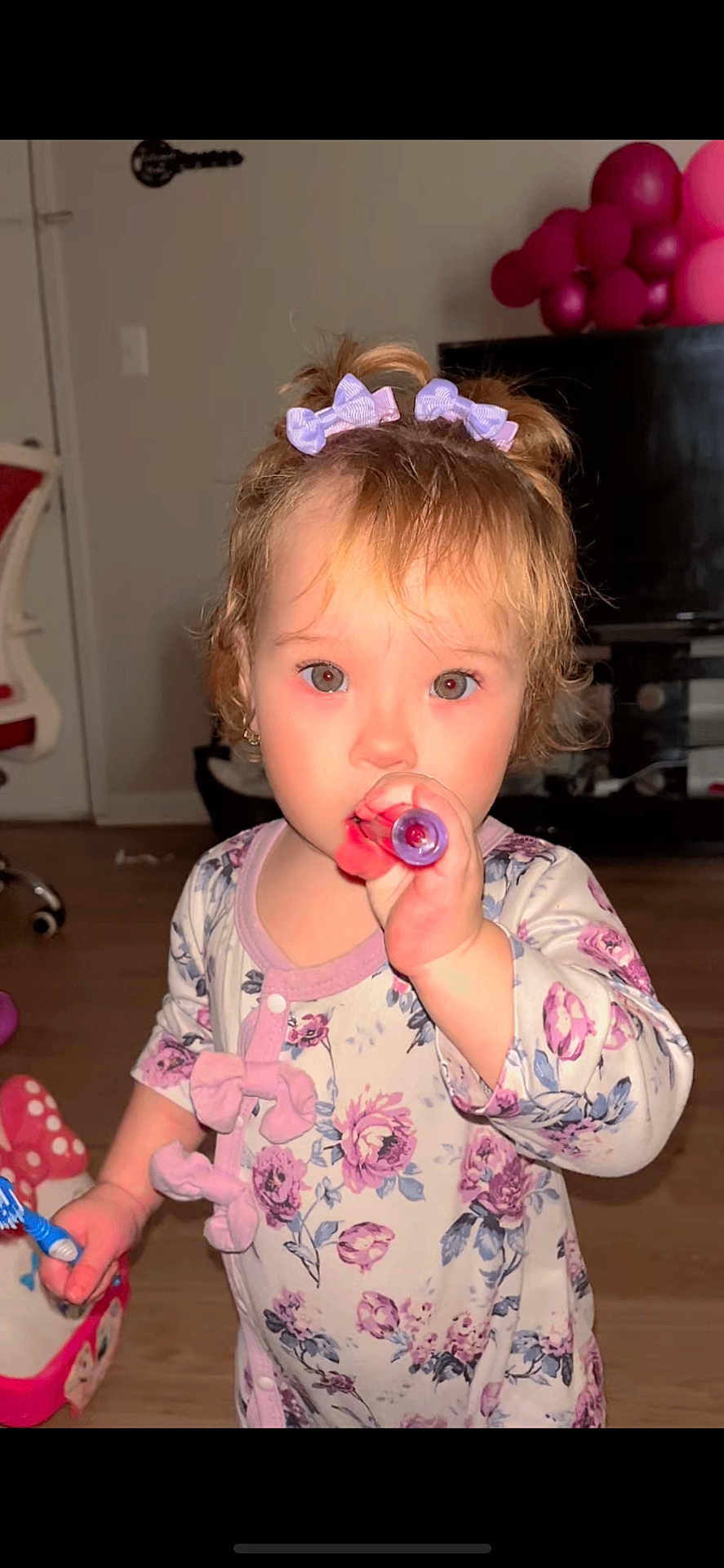 Victoria González joined the competition — help win amazing prizes! toddler, child, girl, indoor, toy, hair_bow, floral_clothing, curious, playing, face, person, floor, furniture, balloons, pink, purple, cute, young_child, home, portrait