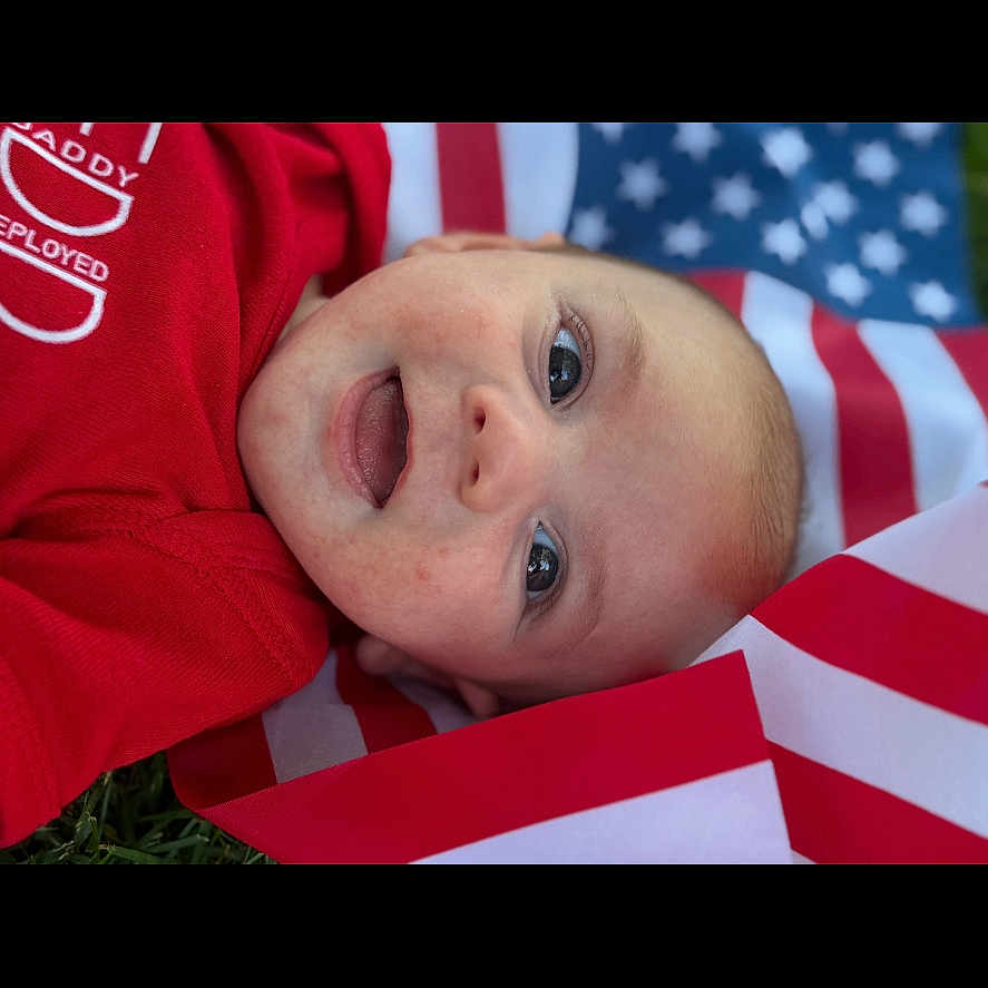 Barrett is registered to the contest to win money with this photo: american_flag, baby, celebration, child, closeup, cute, expression, eye, face, grass, happy, infant, lying_down, outdoor, patriotic, portrait, red_clothing, skin, smile, young