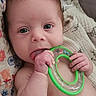 baby, infant, teething_toy, blanket, diaper, hand, face, blue_eyes, soft_hair, colorful, markers, patterned_fabric, cute, lying_down, skin, expression, indoors, child, young, playful