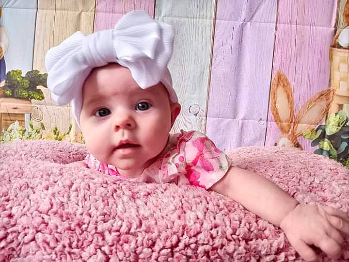 Octavia is registered to the contest to win money with this photo: baby, baby_toddler_clothing, cheek, child, comfort, finger, grass, happy, headgear, headwear, linens, lip, magenta, pattern, person, petal, pink, plant, purple, skin