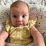baby, infant, yellow_clothing, blanket, cute, wide_eyes, face, arm, pillow, animal_print, bee_design, soft_texture, child, indoors, portrait, looking_at_camera, curious_expression, head, smile, snuggled